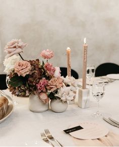 the table is set with candles and flowers in vases, plates and utensils