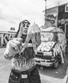 a man with tattoos on his arm making the v sign while standing in front of a truck