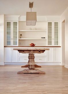 a kitchen with white cabinets and an island in the middle of the room, surrounded by wood flooring