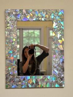 a woman taking a photo with her camera in front of a wall mirror that is made out of mosaic tiles