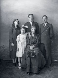 an old black and white photo of a family posing for a photograph in front of a wall