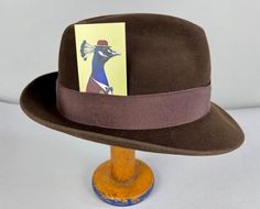 "You'll need this snazzy 1950's fedora to complete your look and turn your suit into an outfit! This fur felt fedora is chocolate brown with a cedar brown grosgrain ribbon band. It has a leather hat band and is fully lined. Made by \"Biltmore\" and sold by \"The Hat Guys\" in Oakland California. This hat is in great vintage condition with no holes, stains, or odors to note. Marked Size: 7 Inner circumference: 22\" Length (at longest point): 11.5\" Width (at widest point): 10.5\" Crown Height: 4\ Vintage Flat Bill Hat For Kentucky Derby, Fitted Fedora With Short Brim For Derby, Vintage Fedora For Kentucky Derby With Flat Bill, Retro Short Brim Top Hat For Kentucky Derby, Retro Fitted Fedora With Curved Brim, Fitted Retro Fedora With Curved Brim, Retro Fedora With Curved Brim, Fitted Vintage Brown Fedora, Retro Fedora With Curved Brim For Kentucky Derby