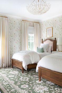 two beds in a bedroom with floral wallpaper