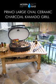 an outdoor grill on a wooden table with bottles and utensils next to it