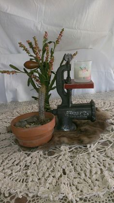 an old fashioned sewing machine and potted plant on a lace doily tablecloth