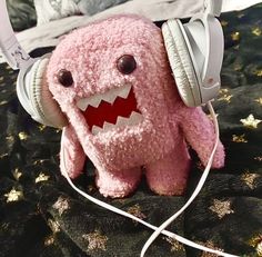 a pink stuffed animal wearing headphones on top of a bed