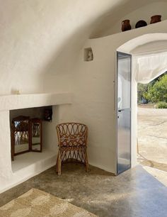 a chair sitting in front of a white wall next to a doorway and mirror on the wall