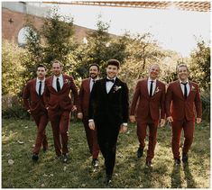 a group of men in red suits standing next to each other on top of a lush green field