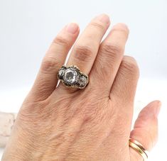 a woman's hand wearing a ring with an oval shaped diamond in the center