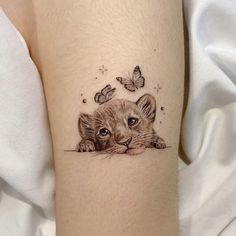 a small tiger cub with butterflies on its head and behind it is a butterfly tattoo