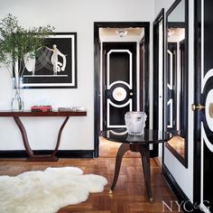 a black and white hallway with art on the wall, rugs and table in front of it