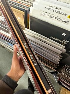 a person holding up some skis in front of a stack of books and records