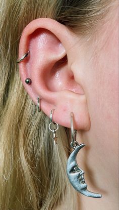 a close up of a person wearing some kind of earring with the moon on it