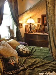 a cat sitting on top of a bed next to a window