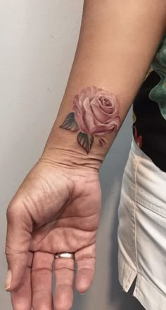 a woman's hand with a rose tattoo on the left side of her arm