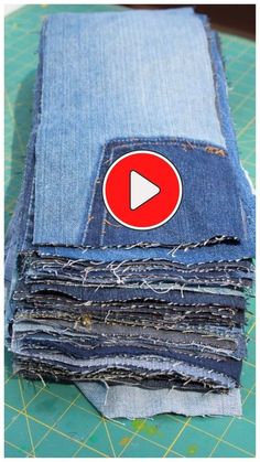 a pile of blue jeans with a red play button on the front and back side