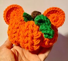 a crocheted orange and green teddy bear with leaves on it's head