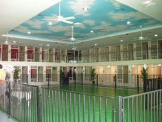 an indoor tennis court with green grass and blue sky painted on the ceiling