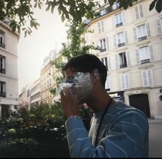 a man standing in front of a building while holding a camera up to his face