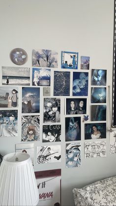 a white wall covered in photos and pictures next to a lamp shade on a bed