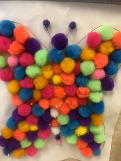 a butterfly made out of pom - poms on top of a piece of paper