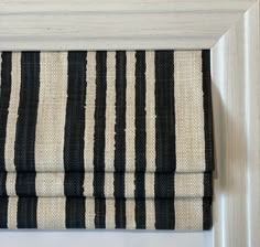 a black and white striped roman blind hanging on a wall in front of a mirror