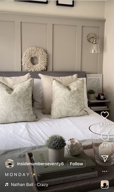 a bed with pillows and some books on top of it next to a table that has a potted succulent