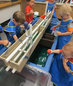 three children in blue uniforms are working on an assembly line with plastic pipes attached to them