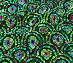 an image of colorful beads on black fabric with green and blue circles in the center