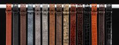 a row of different colored belts hanging from a metal bar in front of a black background