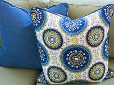 a blue and white pillow sitting on top of a couch next to a green chair