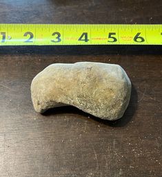 a rock sitting on top of a wooden table next to a ruler