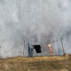 an image of clothes hanging out to dry on a line in front of a gray wall