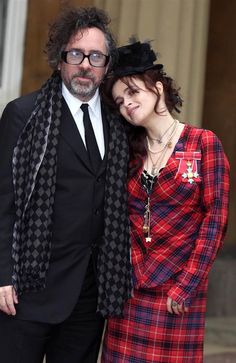 the man and woman are dressed up in black and red outfits, posing for a photo