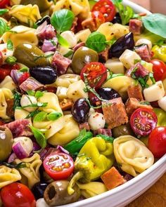 pasta salad with olives, tomatoes, mozzarella and other toppings in a white bowl