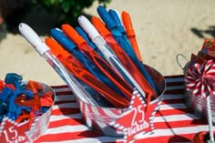 red, white and blue pens are in buckets on a table