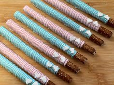 six different colored candy sticks on a wooden table with white and blue icing around them