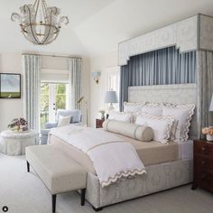 the bedroom is decorated in white and gray colors with chandelier, bed linens,