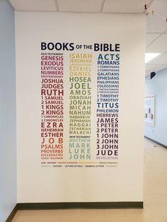 a white wall with books of the bible written in multicolored letters on it