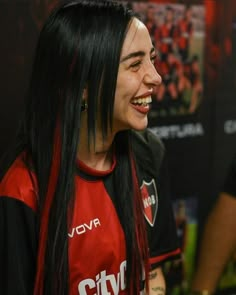 a woman with long black hair smiling at someone