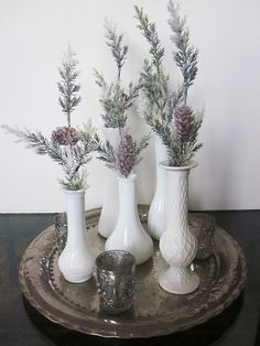 four white vases with flowers in them on a tray