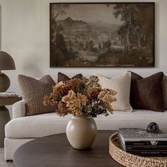 a living room filled with furniture and a painting on the wall above it's coffee table