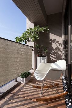 a white rocking chair sitting on top of a wooden floor next to a planter