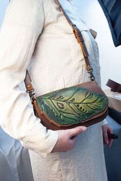 This light brown with green leather small bag with tooled and hand painted leaf is a high-quality and durable accessory that will elevate your style. It is made from the best materials to ensure its longevity. The thick and durable genuine leather, along with steel rivets and strong threads, make this bag sturdy and long-lasting.  With a size of  W - 22 cm (8.6'),  D - 7 cm (2.7'),   H - 12 cm (4.7'),  this bag is suitable for various occasions and can easily accommodate your essentials.  The le Leather Small Bag, Leather Bags Women, Fabric Painting On Clothes, Celtic Style, Painted Clothes, Painted Leaves, Leather Bags Handmade, Ethnic Style, How To Make Ornaments