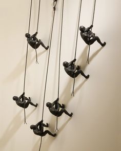 several black figurines hanging from chains on a wall