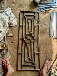 a man standing next to a metal grate on top of a dirt ground with his feet up