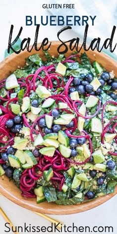 blueberry kale salad in a wooden bowl with red onions and avocado