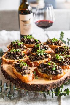 a wooden platter topped with lots of food next to a bottle of red wine