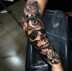 a woman's arm with a skull and flower tattoo on the left side of her leg