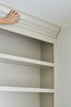 a person is painting the inside of a white bookcase with paint rollers on it